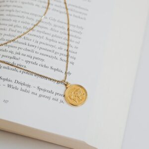 Gold necklace elegantly draped over an open book, creating a serene and minimalistic aesthetic.