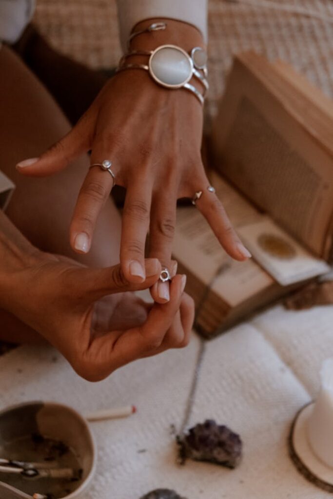 Home Close-up of hands showcasing elegant rings and bracelets against a cozy background.